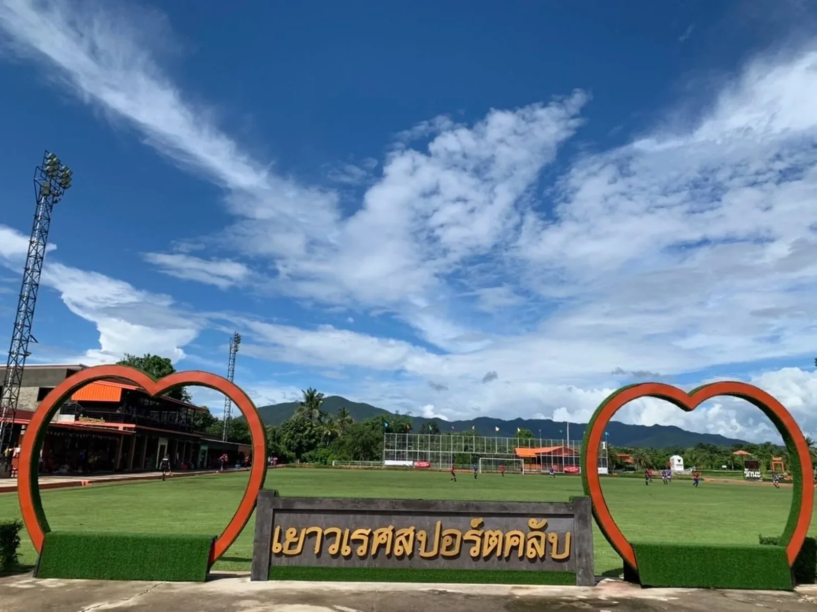 The Yaowarate Sport Club sign and heart-shaped arches in front of the pitch