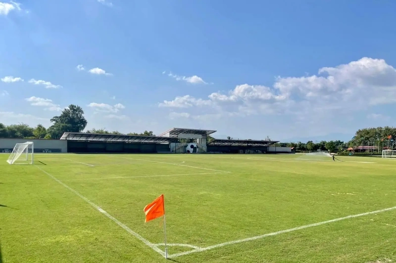 An orange corner flag on the pitch with the stand building behind