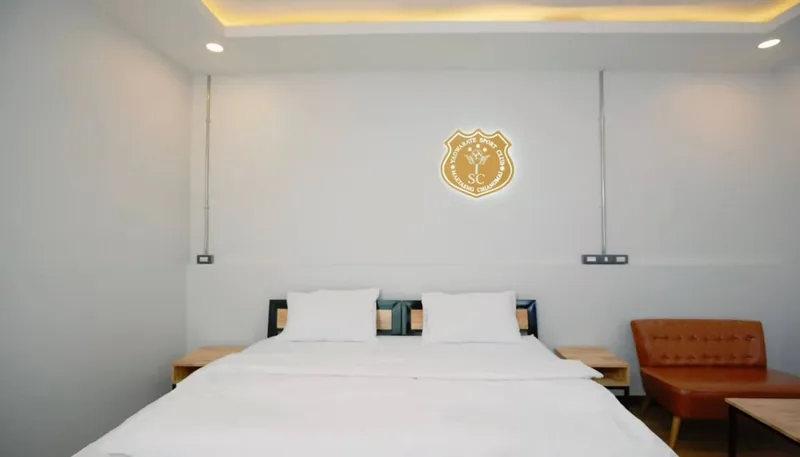 A hotel room with a large white bed and the club crest on the wall