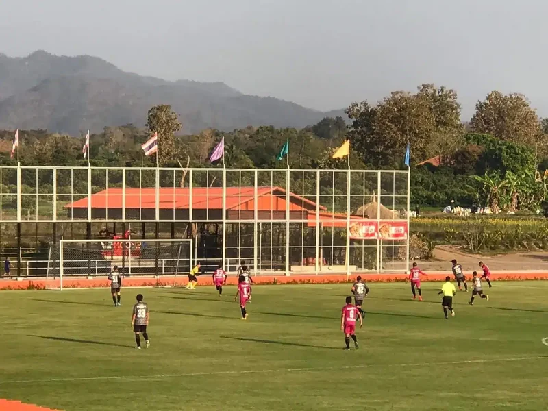 Two teams in a match in front of the orange-roofed stand