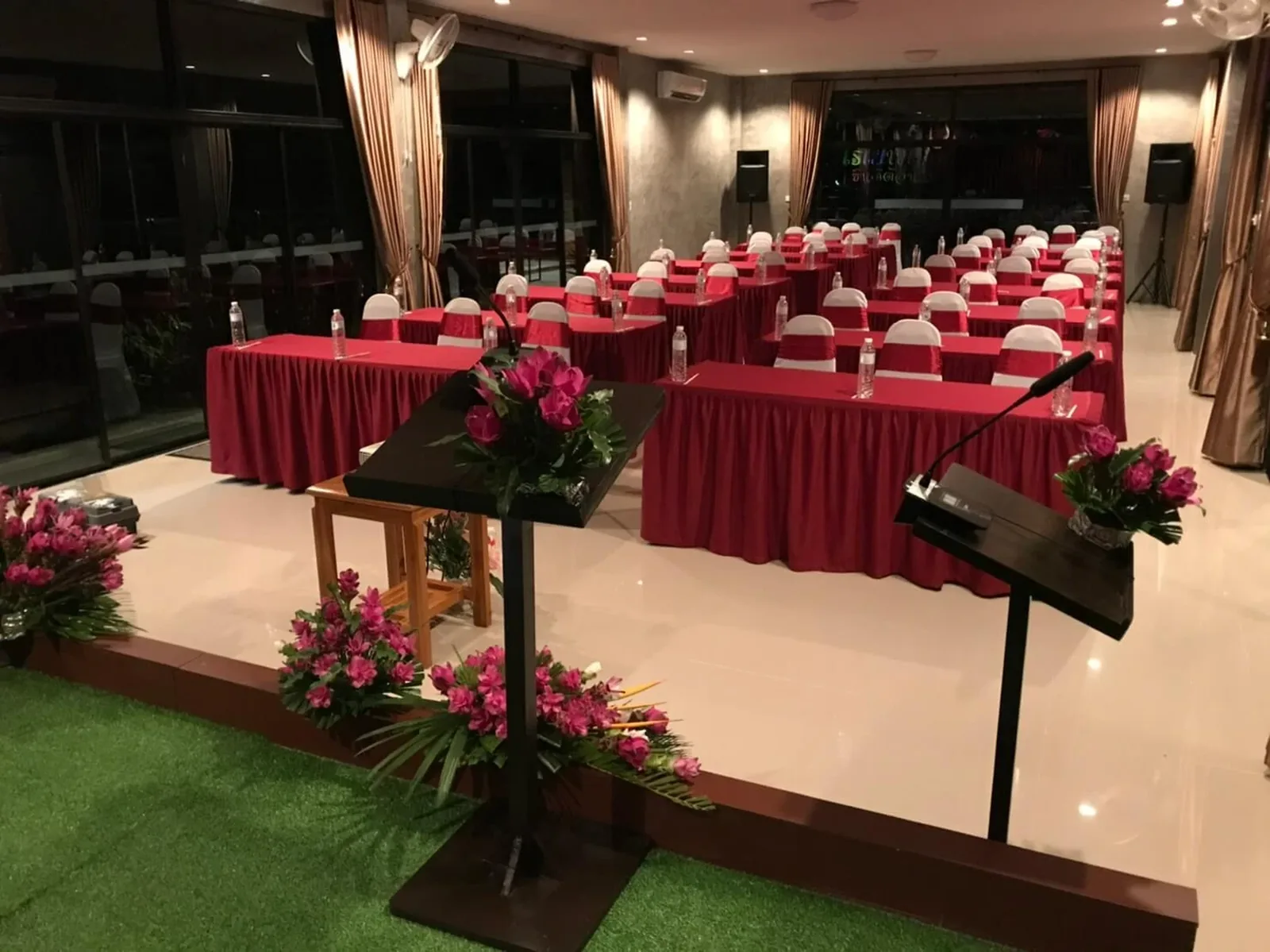 The meeting hall set with red tablecloths, flowers and a lectern
