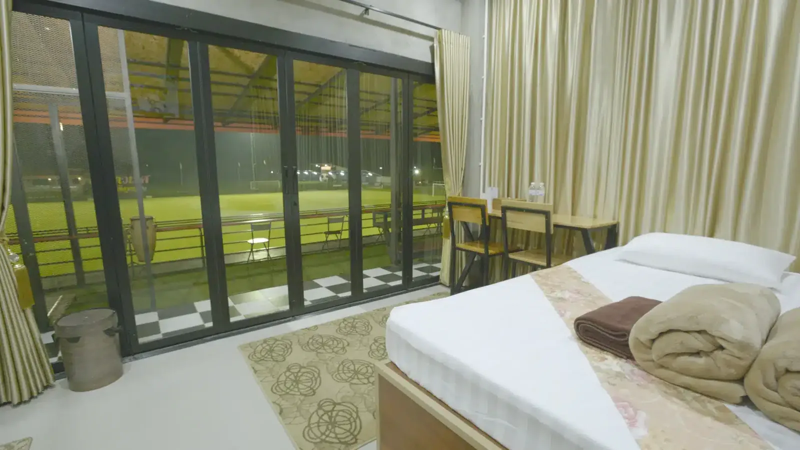 A guest room with glass doors looking straight onto the floodlit pitch